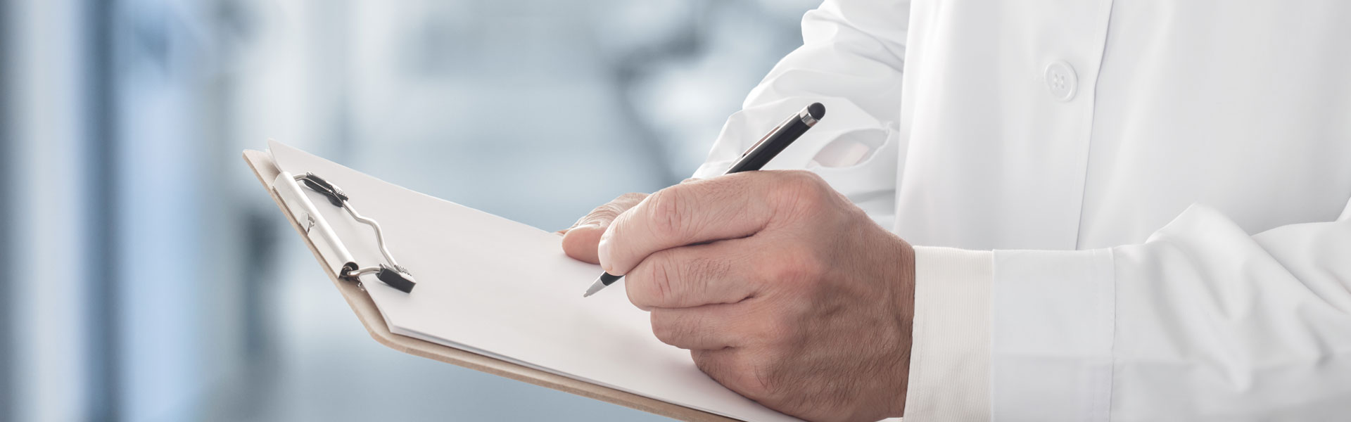 Male doctor holding clipboard filling up medical form